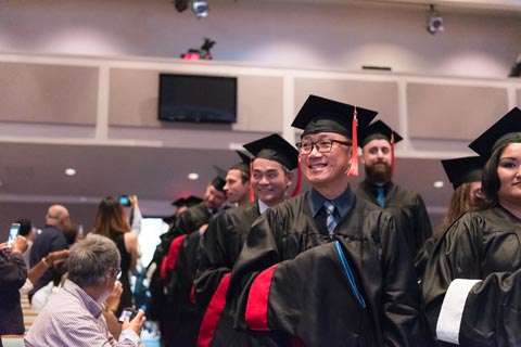 Graduates smiling while anticipating walking to front for diploma.